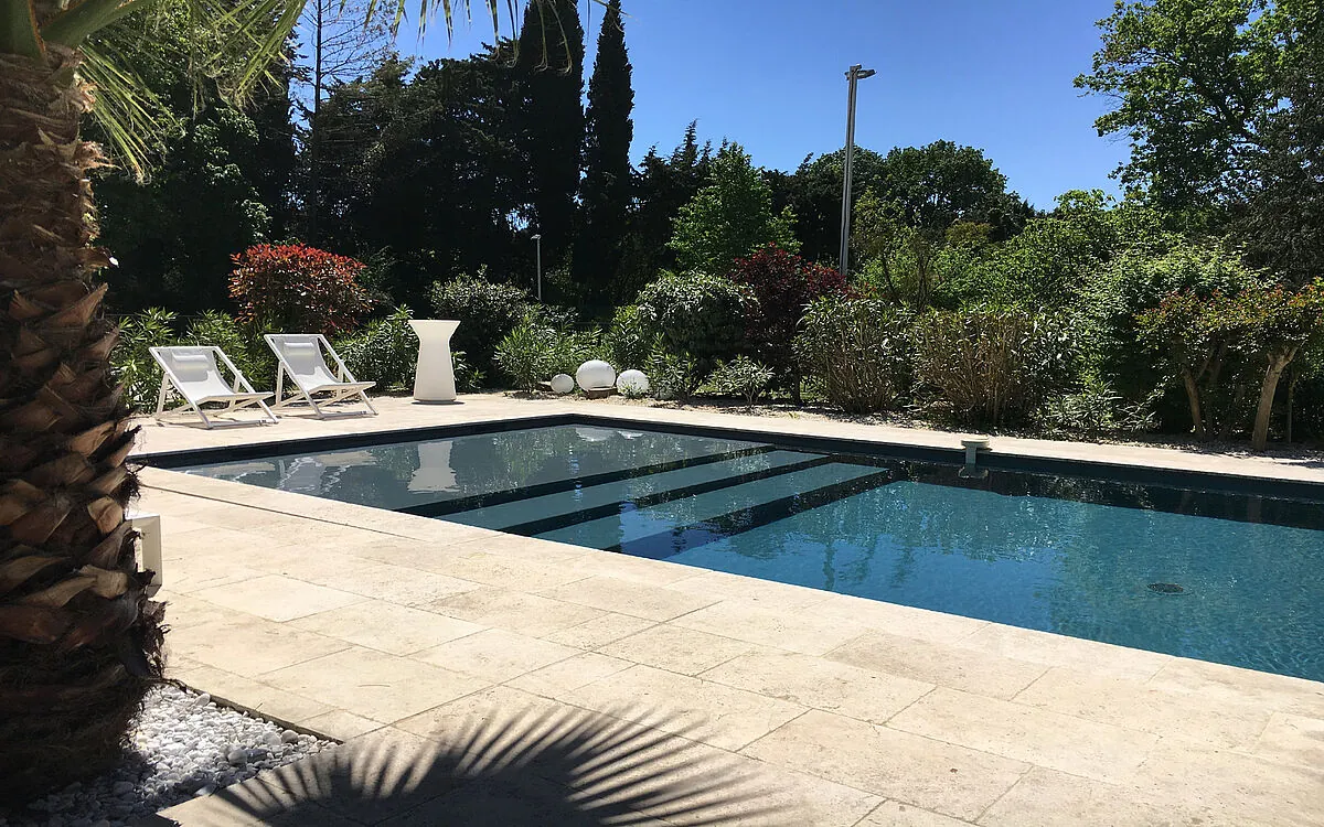 Piscine avec membrane armée RENOLIT ALKORPLAN 2000 Gris Anthracite, eau sombre à l’effet miroir dans un jardin méditerranéen