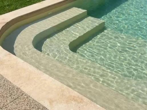 Marches arrondies de piscine avec membrane armée BWT Be BRANE 3D Surface Tuscan Sun, teinte sable chaud et eau turquoise claire