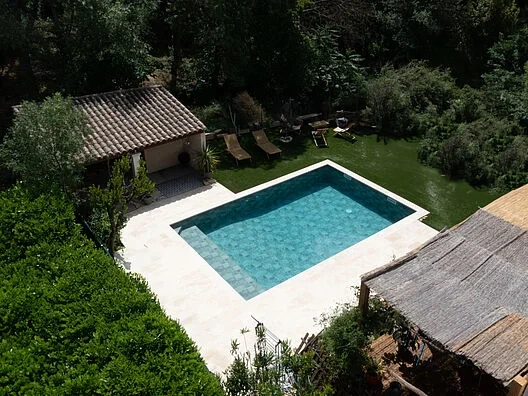 Vue aérienne d’une piscine avec membrane armée RENOLIT ALKORPLAN Ceramics Evolve Verdant, eau bleu-vert sauge entourée d’un jardin méditerranéen arboré