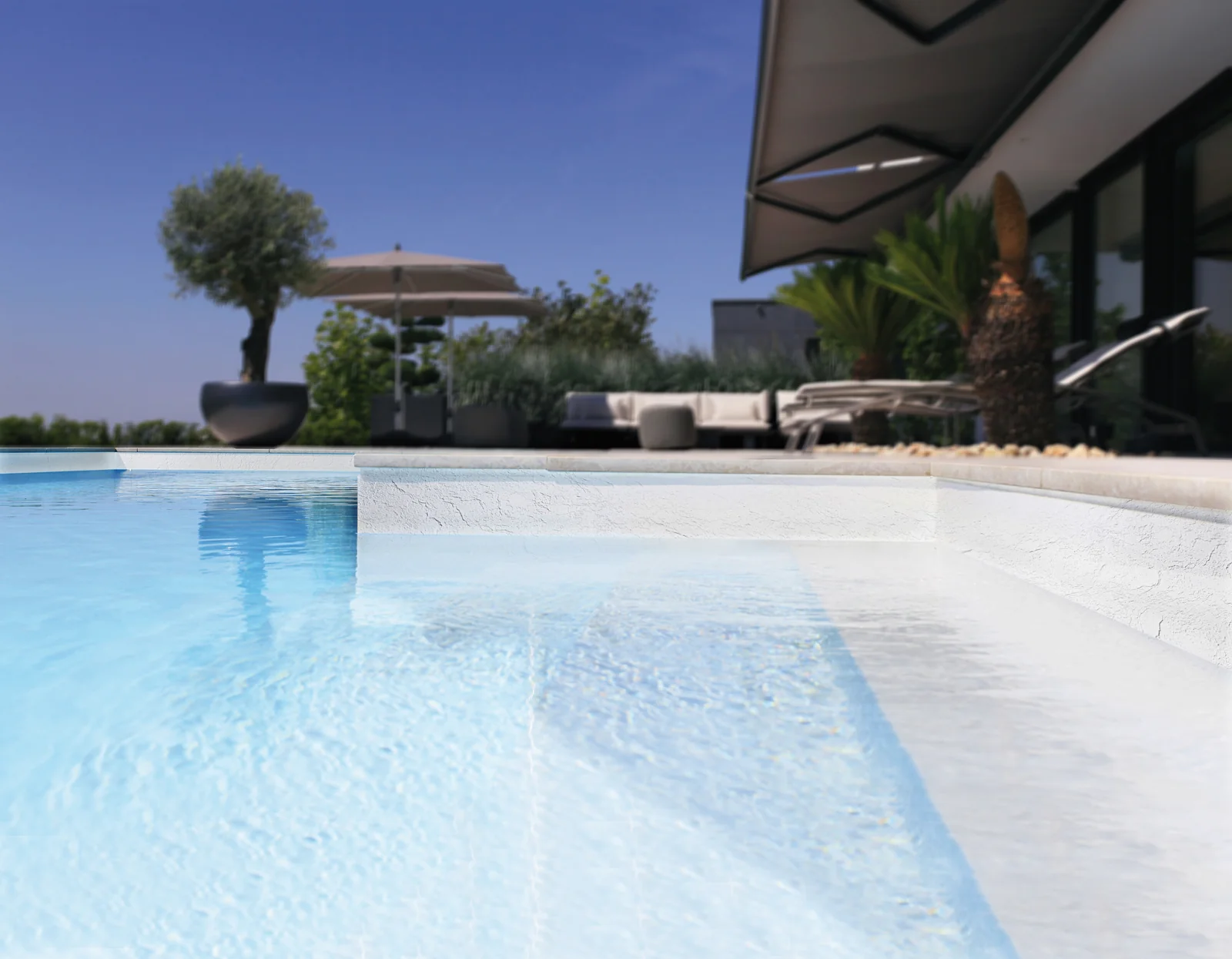 Piscine avec membrane armée RENOLIT ALKORPLAN Relief Blanc, paroi texturée blanche en terrasse face à une villa contemporaine