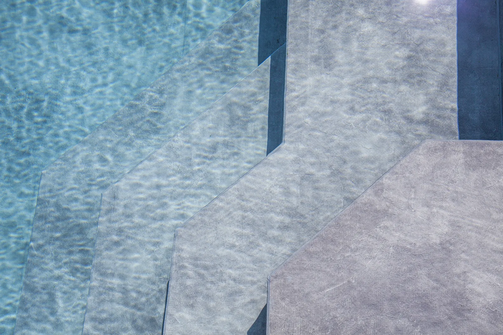 Marches de piscine avec membrane armée RENOLIT ALKORPLAN Vogue Urban, effet béton gris et eau turquoise cristalline