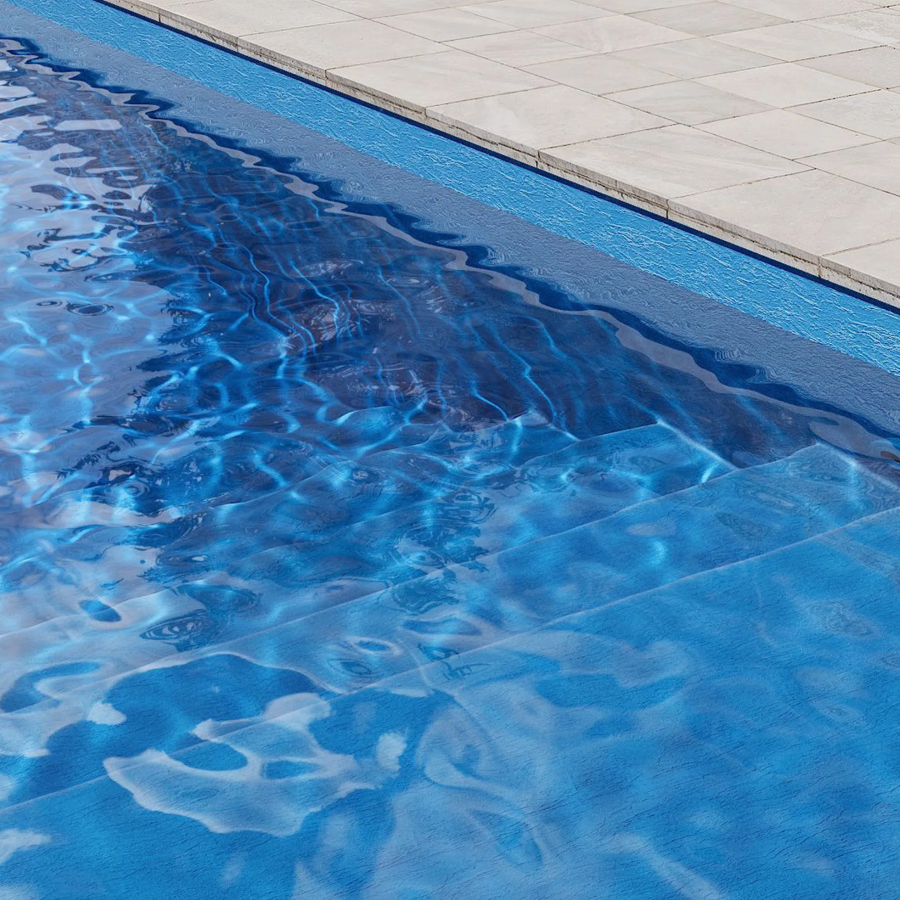 Marches de piscine avec membrane armée BWT Be BRANE Pureline Bleu Adriatique, eau bleu intense et profonde sur une terrasse en bois